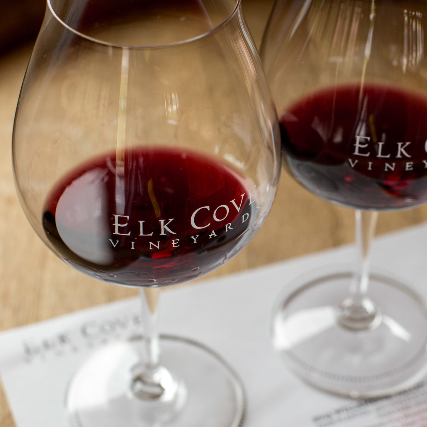 three glasses of pinot noir with elk cove logo on paper with a pen
