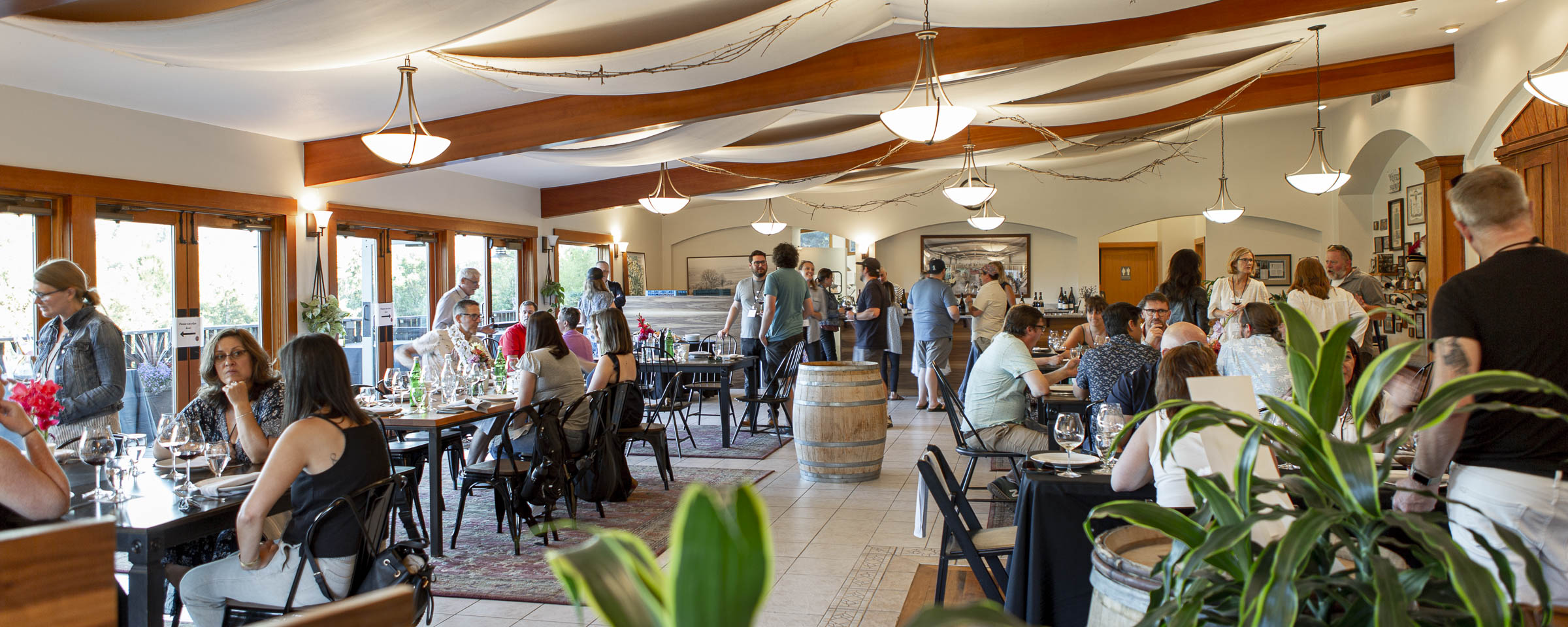 tasting room with tables and chairs and white ceilings with wooden beams and houseplants